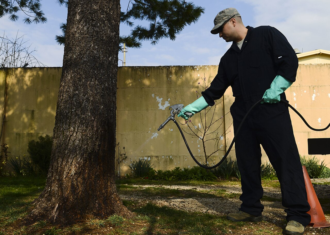 Pest control technician treating an outdoor area
